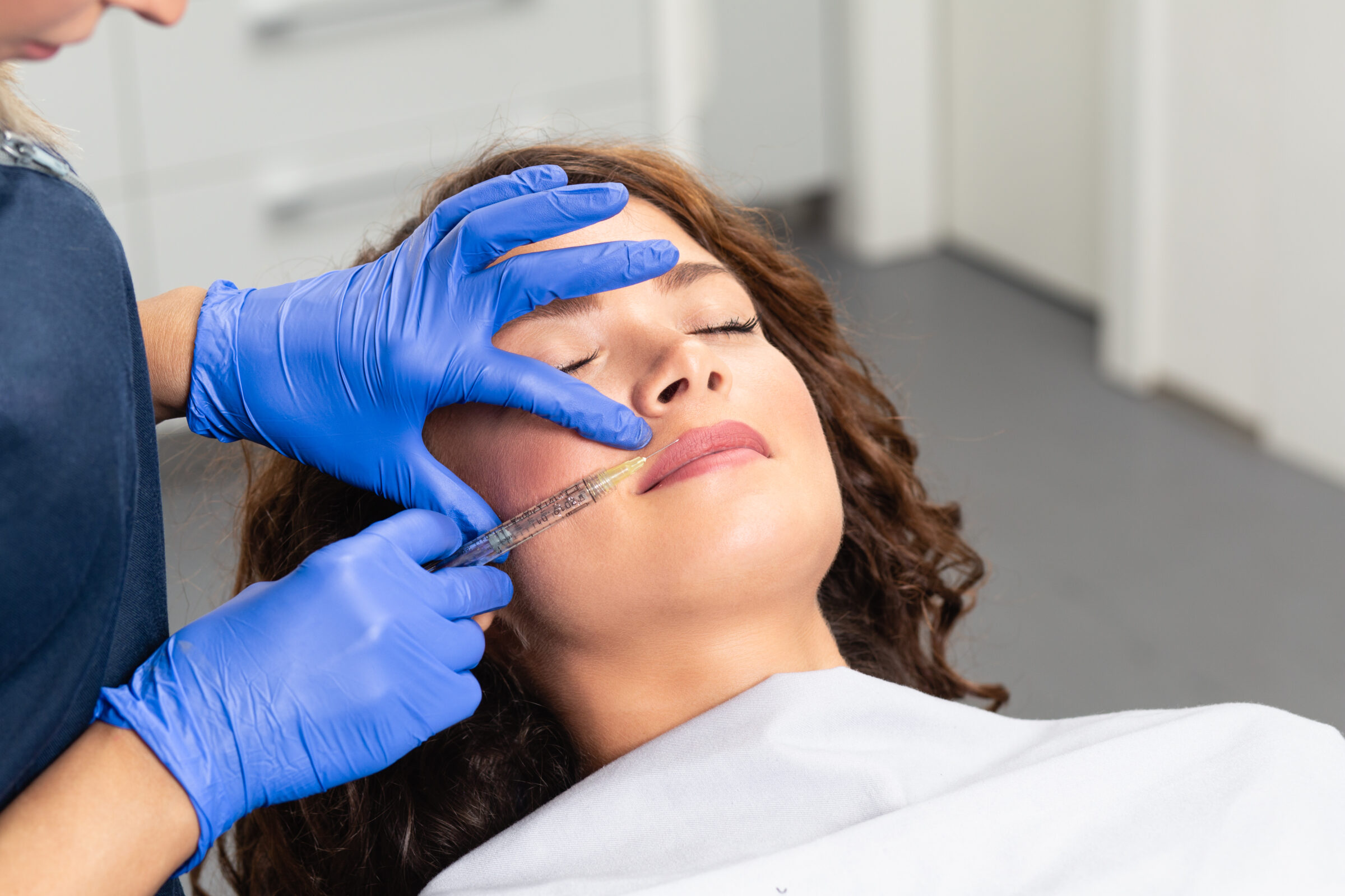 A brunette woman getting a botox injection in her face.