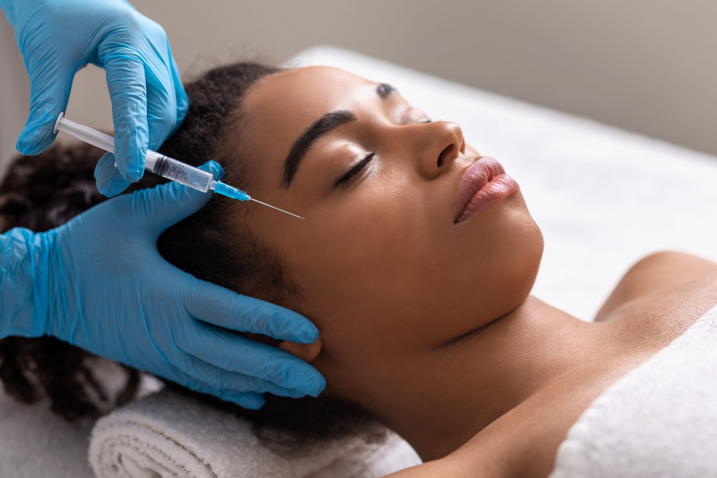 An Africa American woman getting a Sculptra injection in her face